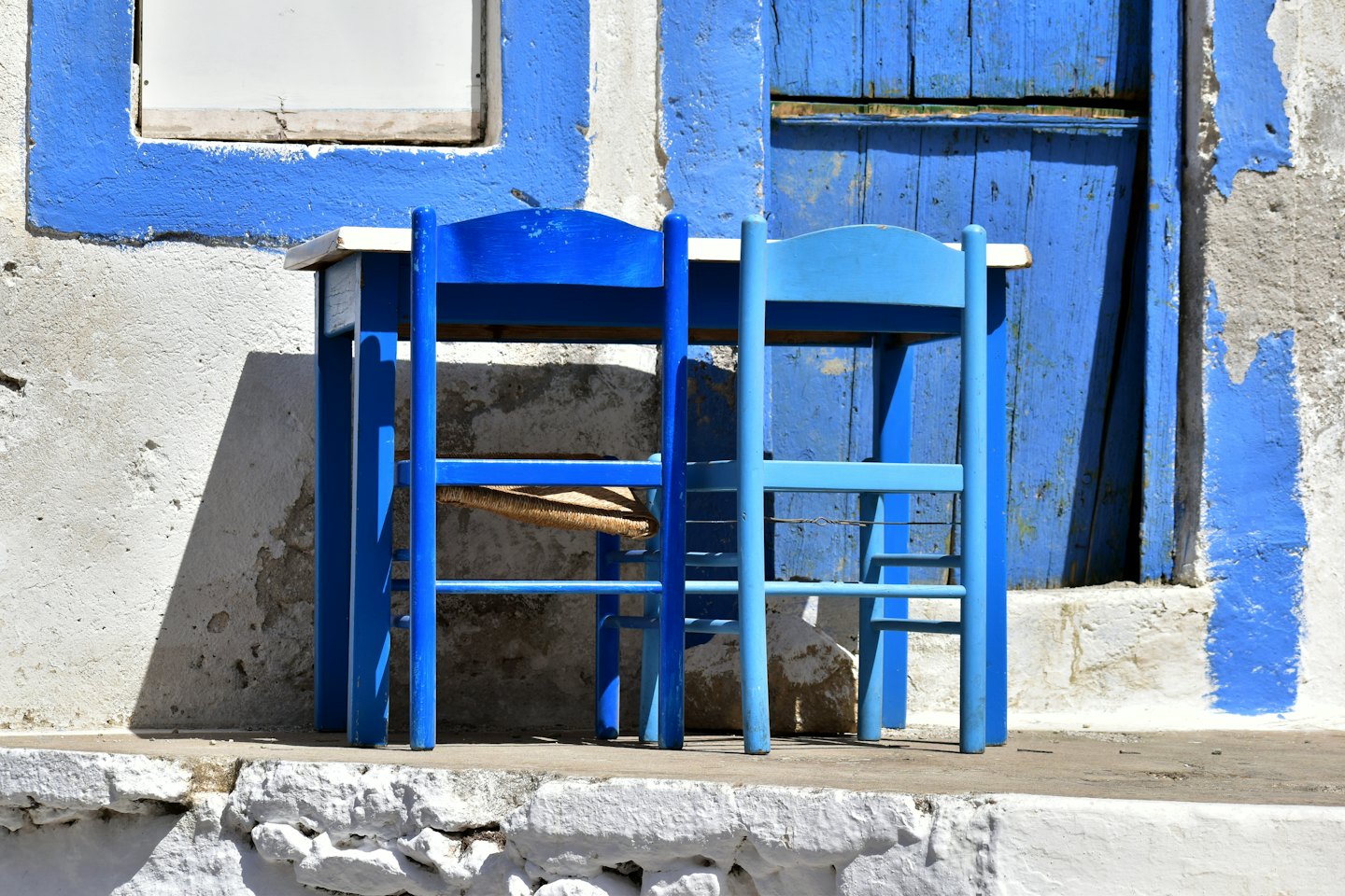 Tavolo e sedie blu all'esterno di un edificio imbiancato a calce.