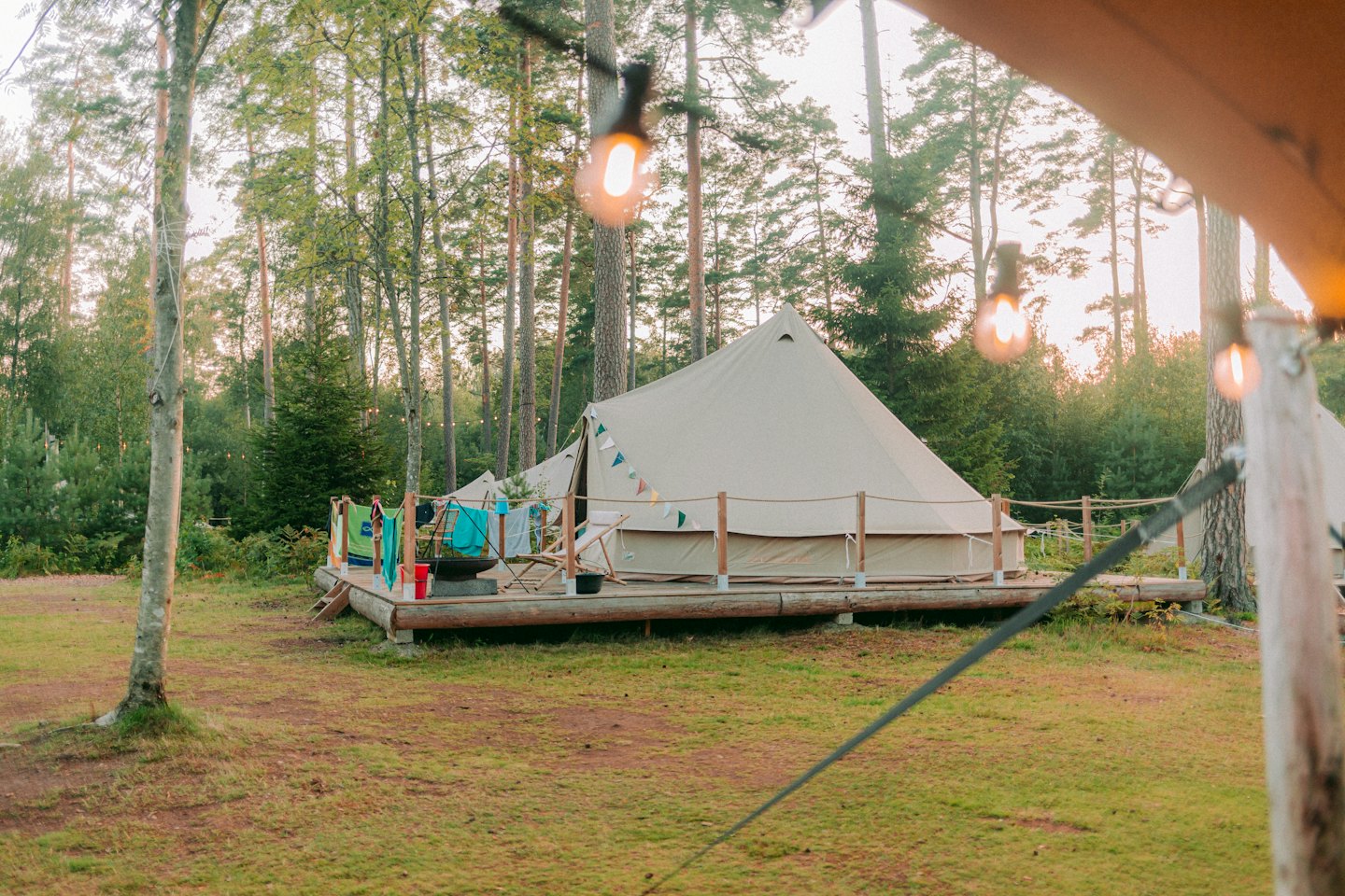 Tenda a campana su una piattaforma di legno in una foresta al tramonto.