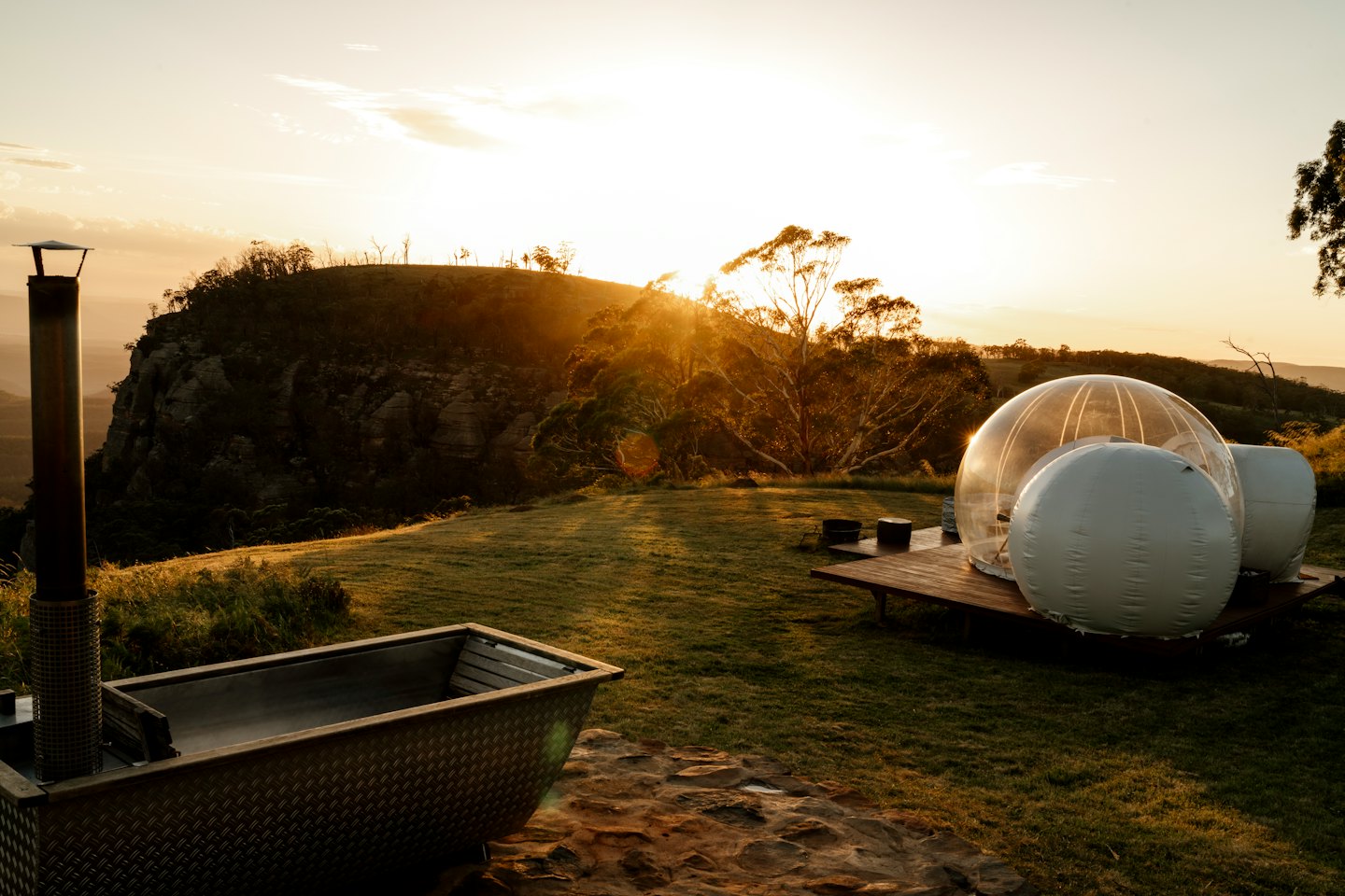 Tenda a bolla trasparente per glamping sul ponte al tramonto.